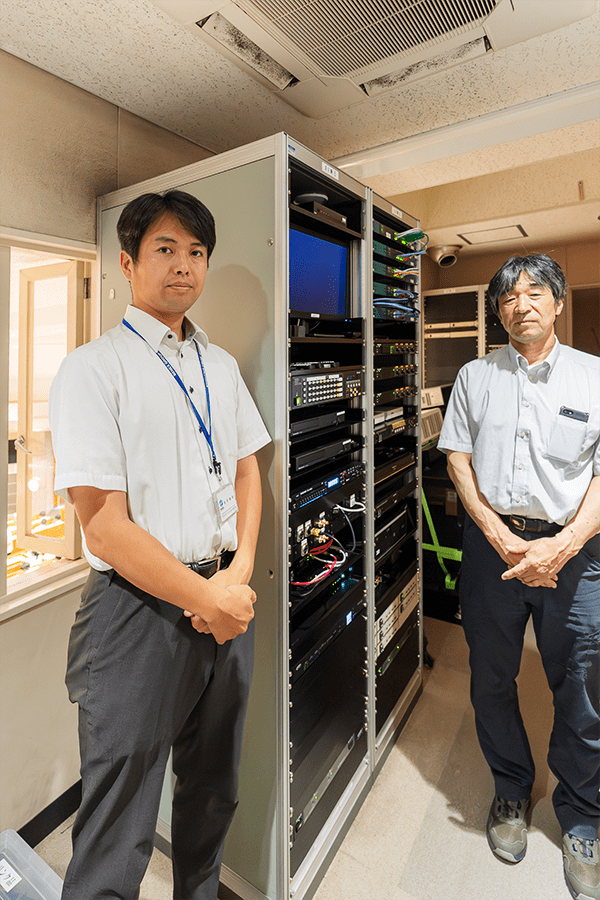 【S201講堂のコントロールルームにて　ベネックスソリューションズ　秋吉様　（左）、野口様　（右）】